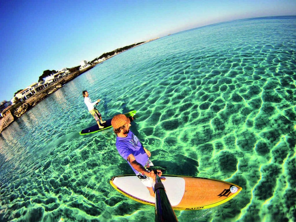 Paddler pe o placă de SUP navigând pe apele cristaline din Menorca. Experiență de neuitat de SUP în Menorca.